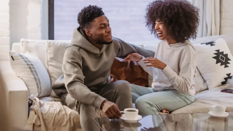 A couple talking and laughing together on a sofa at home