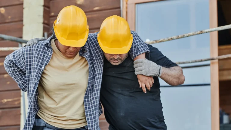 A worker helping an injured co-worker on a building site